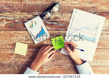 business, statistics and people concept - close up of female hands with charts and eyeglasses on table