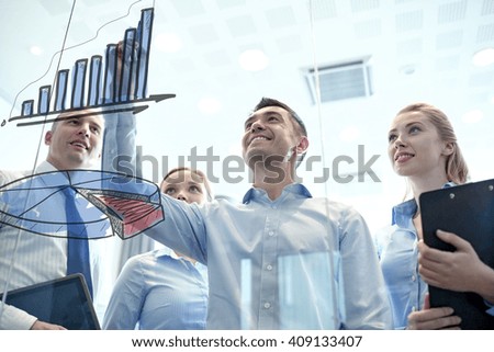 Man drawing a bar graph with other people behind him and a pie graph on the foreground 