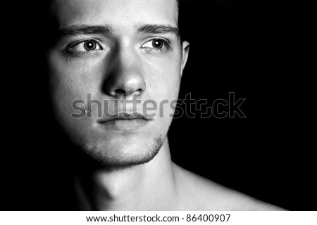 Portrait of sad man cry with tear on his cheek. Look to the side. Glare in his eyes. Black and white.