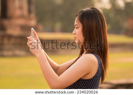 female using smartphone taking a photo at sight seeing place  in Thailand ancient temple