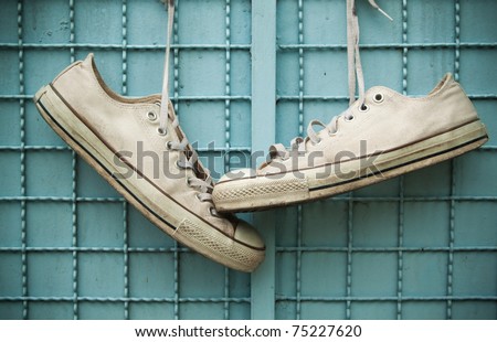 pair of old sneakers hang on blue wall