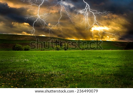 Thunderstorm with lightning in green meadow.