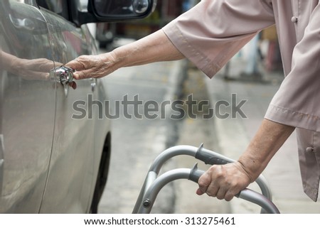 senior woman open car door with walker on street.