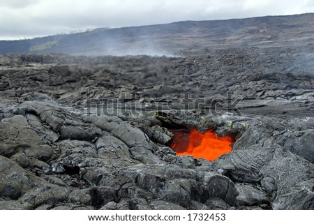 Heat rising from a glowing lava skylight (an opening in the roof of a lava tube) seen on a lava adventure hike - Hawaii Volcanoes National Park