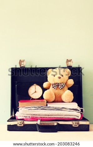 open case with books towel teddy bear and vintage clock. vacation concept.
