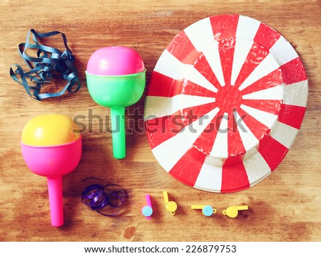 top view of vintage party  accessories - party hat maracas whistles and confetti over wooden board.