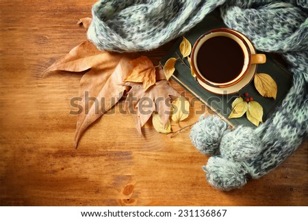 Top view of Cup of black coffee with autumn leaves, a warm scarf and old book on wooden background