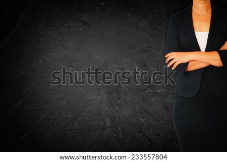 Close up of businesswoman with arms crossed against dark textured background
