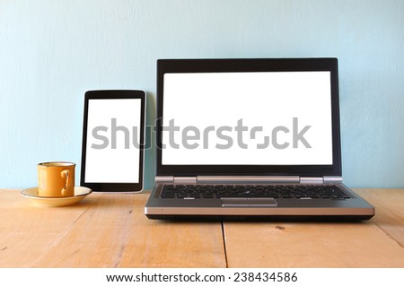 tablet device and laptop with blank white screens ready for mock up over wooden table