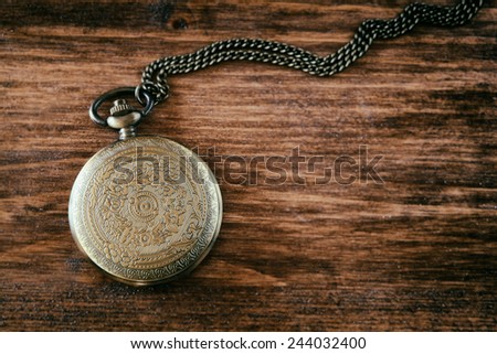 macro image of old vintage pocket watch on wooden table. top view. retro filtered image