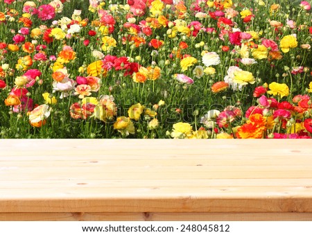 wood board table in front of summer landscape of field with many flowers