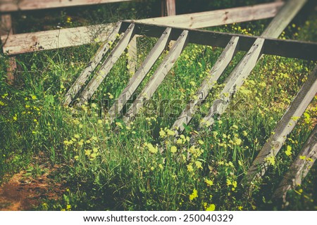 image of broken wooden fence in field of flowers. image is faded style filtered