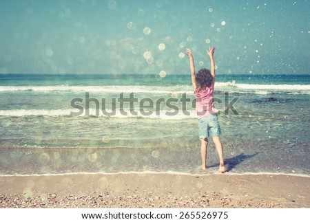 cute happy kid (girl) playing at the beach. toned image with glitter overlay
