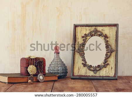 image of victorian vintage antique classical frame, jewelry and perfume bottles on wooden table. filtered image