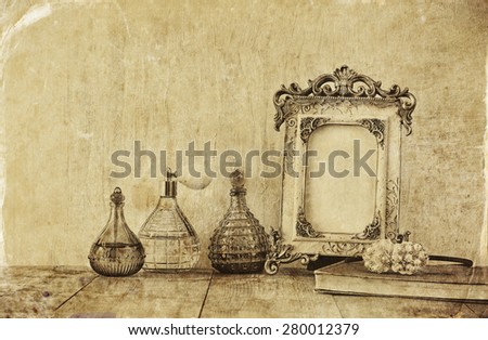 image of victorian vintage antique classical frame and perfume bottles on wooden table.  old style photo