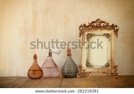 image of victorian vintage antique classical frame and perfume bottles on wooden table. filtered image