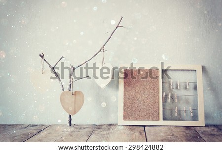 decorative bulletin board with ropes and wooden clothespins and hanging hearts over wooden table. ready for text or mockup. retro filtered image with glitter overlay