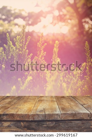 vintage wooden board table in front of dreamy and abstract landscape with lens flare.
