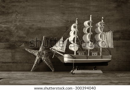 old vintage wooden sailing boat ans starfish on wooden table. vintage filtered image. nautical lifestyle concept. black and white