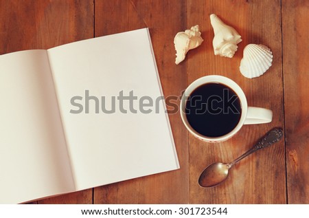 top view image of open notebook with blank pages next to cup of coffee on wooden table. ready for adding text or mockup