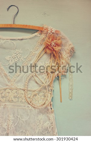 vintage white crochet lace top with hanger on wooden background. retro filtered image