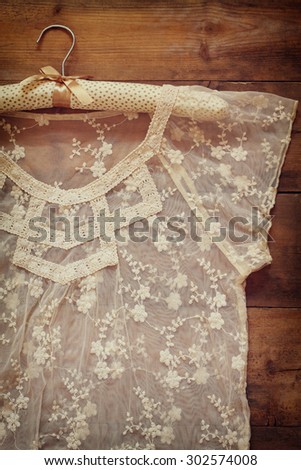 vintage white crochet lace top with hanger on wooden background. retro filtered image