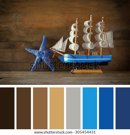 old vintage wooden white sailing boat on wooden table. nautical lifestyle concept. with palette color swatches