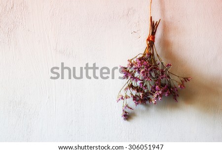 abstract image of bouquet of dried flowers hanging on rope against wooden background at evening light