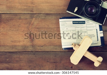 top view image of flying ticket wooden airplane and vintage camera over wooden table. retro filtered image