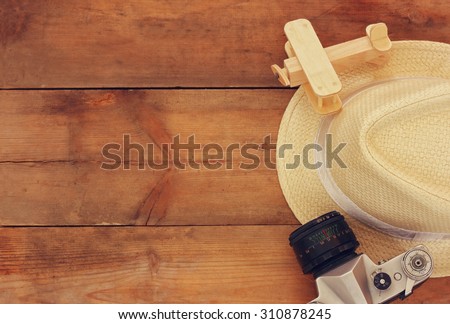 top view image of wood aeroplane, fedora hat and old camera over wooden table