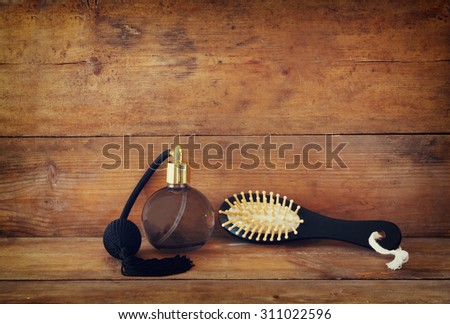 photo of vintage perfume bottle next to old wooden hairbrush on wooden table. retro filtered image