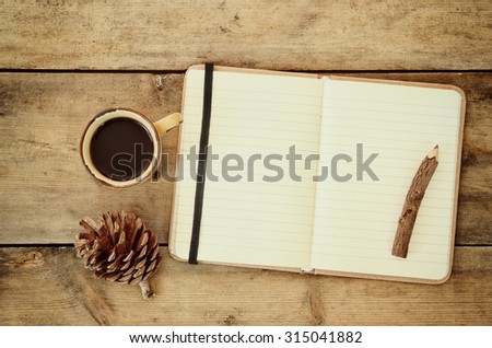 top image of open notebook with blank pages, next to pine cones and cup of coffee over wooden table. top image,