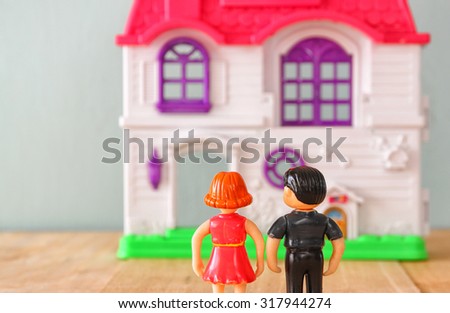 concept image of young couple in front of new house. little plastic toy dolls (male and female) , selective focus.