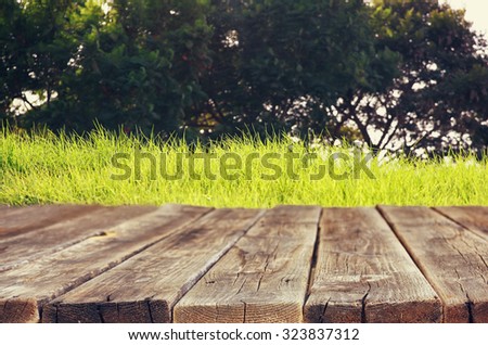 vintage wooden board table in front of meadow landscape with lens flare.