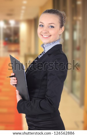 Cheerful beautiful business woman with clipboard writing,