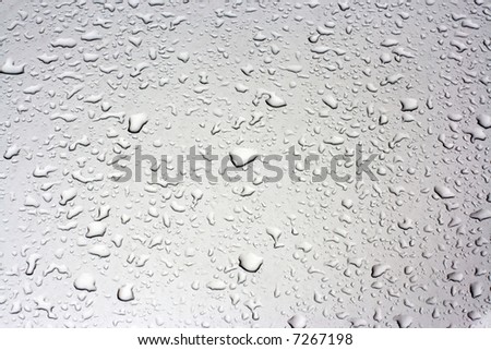 Rain droplets on a grey metallic surface of the car