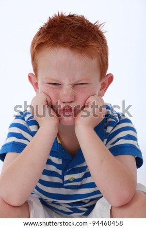 Red head boy wearing blue striped shirt with sad expression on face