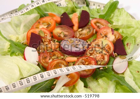 Tomato slices in heart shape on abed of lettuce with salad vegetables, suggesting healthy eating is good for your heart