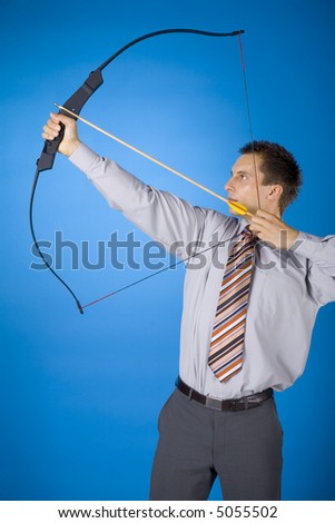 Young businessman holding bow and shooting to target. Blue background