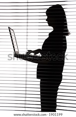silhouette of woman with laptop (view through the blind)