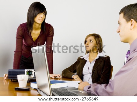 Women and a man having conversation at conference\'s table. There\'re multimedia projector and laptop on it.