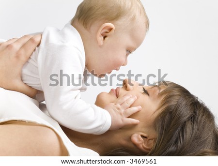 Young mother with baby boy. Lying on bed and hugging. Face to face, side view