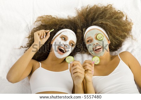 Young women with puryfing mask. Ther're lying on towels.