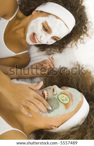 Happy young women lying on towel and putting face mask.
