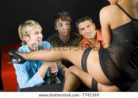 Three men sitting in front of woman in dark room. They are smiling but one looking confused and shocked. Front view