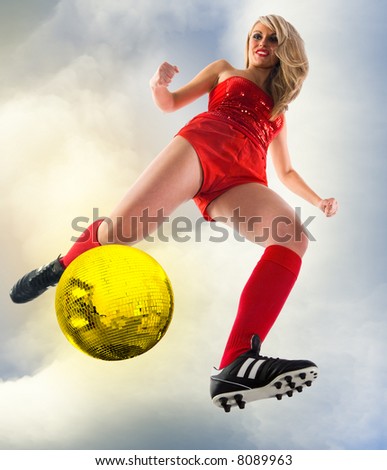 Blonde female soccer player kicking golden disco ball. Unusual angle view - directly below.