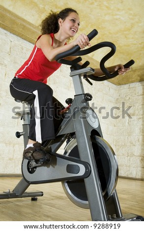 Young woman working out on exercise bike at the gym. Low angle view.