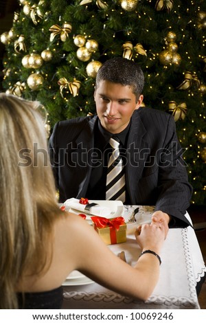 Couple at restaurant on dinner party. They're looking at each other and smiling. Focused on him.