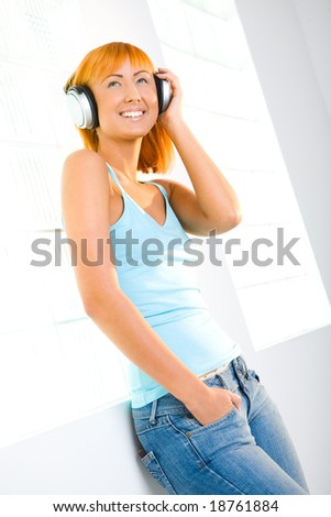 Young sexy woman listening to music by headphones. Low angle view.