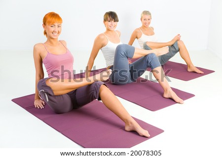 Group of women doing fitness exercise on mat. They're looking at camera.